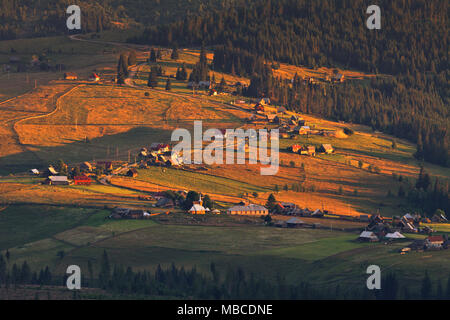 Peaceful mountain village in warm sunset light. Apuseni Mountains, Carpathian Euroregion, Romania. Stock Photo