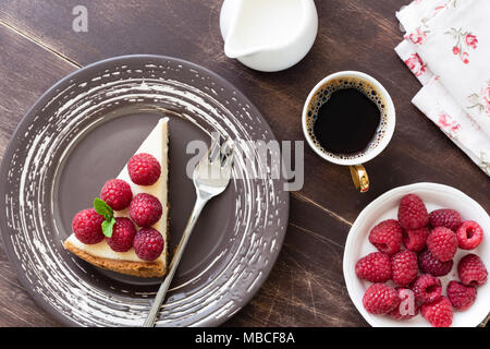 Slice of cheesecake with raspberries and cup of coffee on wood table. Top view Stock Photo