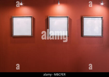Three White Empty Blank Frames On Red Wall. Stock Photo