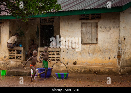 MAKENI, SIERRA LEONE - June 06, 2013: West Africa, Unknown family group as it rains in a small village near Makeni, Sierra Leone Stock Photo