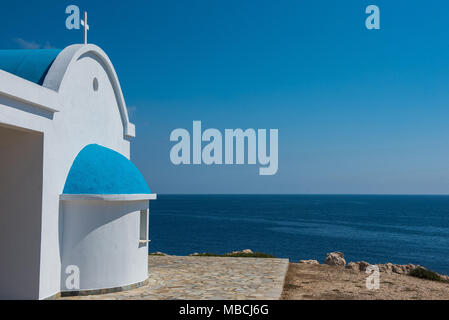Whitewashed church with blue roof near the sea. Agioi Anargyroi chapel, Cyprus Stock Photo