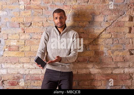 A serious handsome young man pointing to the screen of his smartphone in a sweater. Stock Photo