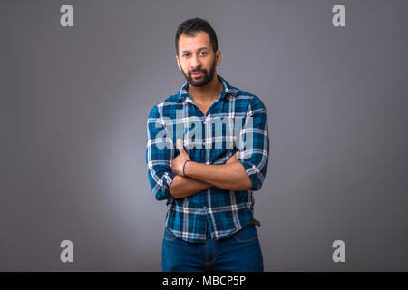 A serious young black man standing confidently with his arms folded Stock Photo