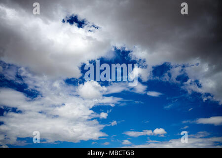 Gathering storm clouds in a sunny blue sky in a full frame background for weather themes Stock Photo