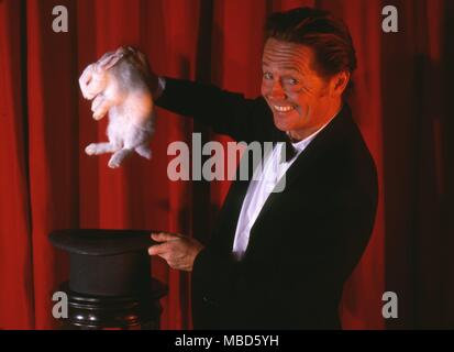 Stage magic - Rabbit from top hat The magician lifting a white rabbit from a hat which has just been shown to be quite empty Stock Photo