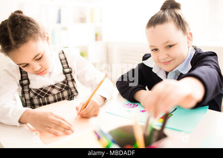 Two girls painting in art school class. Children drawing at the table Stock Photo