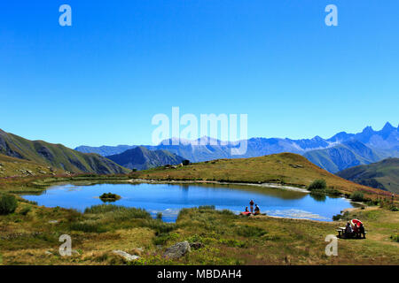 Landscape surrounding the mountain pass Col de la Croix de Fer (Savoy, French Alps): lake and panoramic view of the Alps mountain range Stock Photo