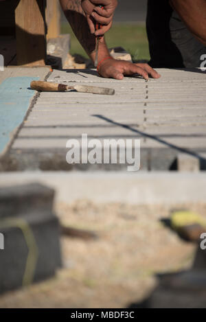 Close up view of worker using tools while laying brick on ground Stock Photo