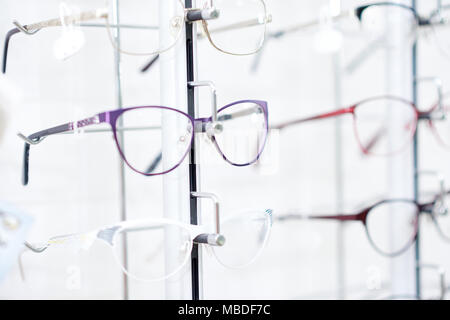 Sideview of fashionable optical eyeglasses, hanging on transparent set with other glasses. Vision improving and protecting. Appointing after medical examination. Stock Photo