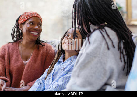 Smiling mother and daughter on sofa Stock Photo