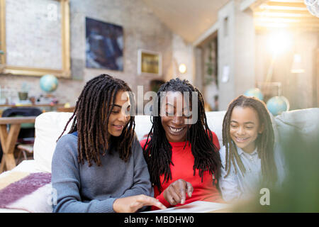 Smiling mother and daughters looking at photo album on sofa Stock Photo