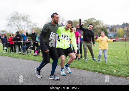 Spectators cheering for man helping injured marathon runner Stock Photo