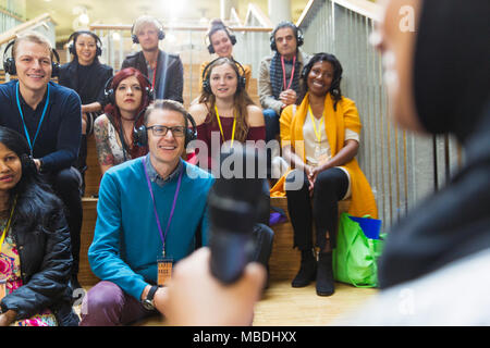 Smiling audience with headphones listening to conference speaker Stock Photo
