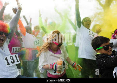 Playful crowd of runners throwing holi powder at charity run Stock Photo