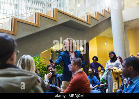 Smiling male speaker giving microphone to woman in audience Stock Photo