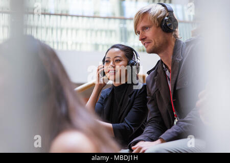 Smiling business people with headphones in conference audience Stock Photo