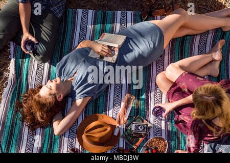 Overhead view young woman with book relaxing on picnic blanket Stock Photo