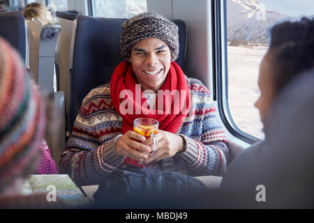 Smiling young man drinking mulled wine on passenger train Stock Photo