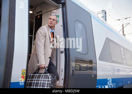 Businessman getting off passenger train Stock Photo