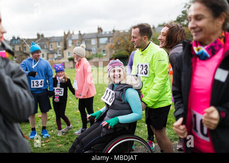 Man pushing woman in wheelchair at charity race in park Stock Photo