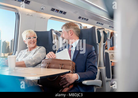 Businessman and businesswoman working, talking on passenger train Stock Photo