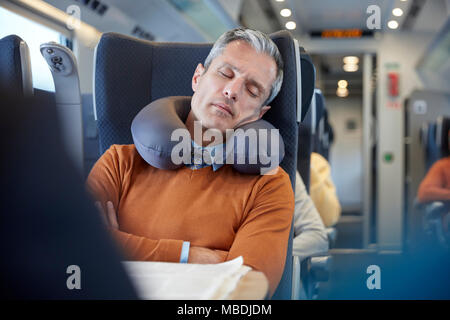 Tired businessman with neck pillow sleeping on passenger train Stock Photo