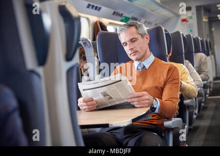 Businessman reading newspaper on passenger train Stock Photo