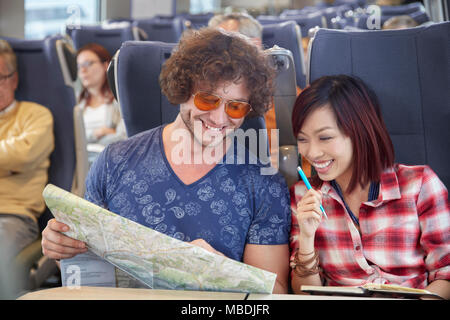 Young couple looking at map on passenger train Stock Photo
