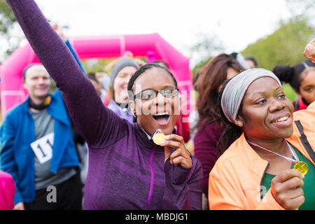 Enthusiastic female runners with medals cheering, celebrating at charity run Stock Photo
