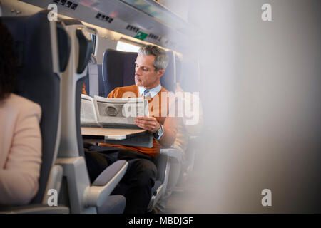 Businessman reading newspaper on passenger train Stock Photo