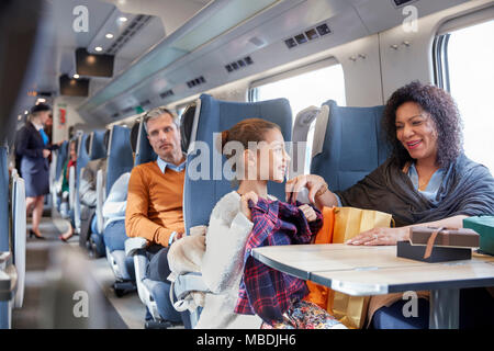 Mother and daughter looking at new clothes on passenger train Stock Photo