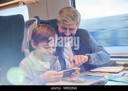 Father and son using smart phone on passenger train