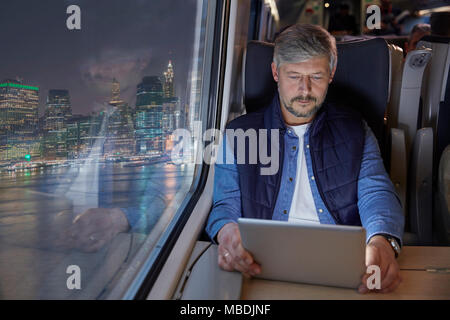 Man using digital tablet on passenger train at night Stock Photo
