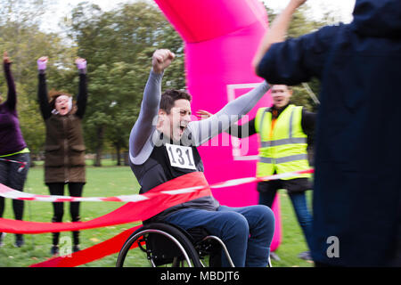 Enthusiastic man in wheelchair crossing charity race finish line Stock Photo