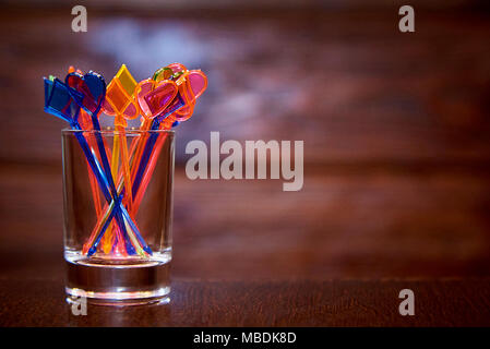 Multi-colored skewers for canapés in a glass cup on a wooden background. Copy space. Stock Photo