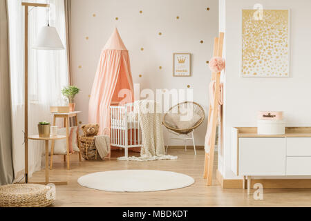 White, round rug and painting in pink and gold kid's bedroom interior with bed under canopy Stock Photo