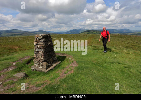Walker at the Ordnance survey trig point, summit of Little Mell Fell, Lake District National Park, Cumbria County, England, UK Stock Photo