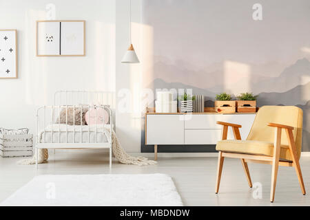 Yellow armchair and plants on white cupboard in child's bedroom interior with mountain pattern Yellow armchair and plants on white cupboard in child's bedroom interior with mountain pattern