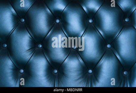 Dark blue capitone genuine leather background, retro Chesterfield style soft tufted furniture upholstery with deep diamond pattern and buttons, close  Stock Photo