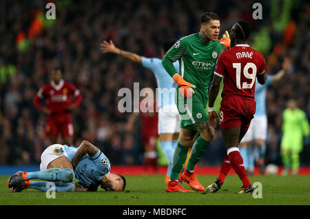 Manchester City's Nicolas Otamendi (left) goes down from a challenge as Manchester City goalkeeper Ederson (centre) confronts Liverpool's Sadio Mane during the UEFA Champions League, Quarter Final at the Etihad Stadium, Manchester. Stock Photo