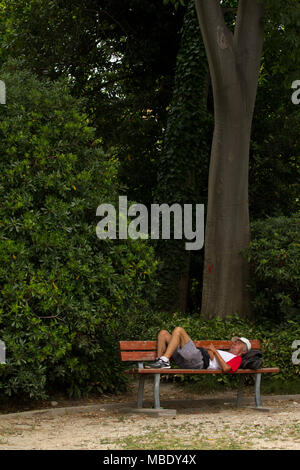 A man asleep on a park bench in a park in Venice, Italy Stock Photo