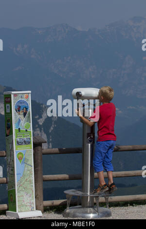 A curious child looking over a mountain range on top of Monte Baldo near the cable car station, Italy Stock Photo