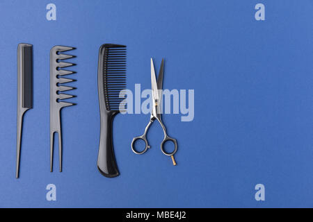flat lay with black hairbrushes and scissors, isolated on blue Stock Photo