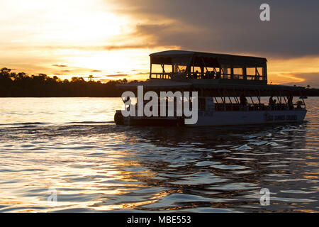 A boat during a sunset cruise on the Zambezi River near Victoria Falls in Zimbabwe. The sunset cruises provide a means of viewing wildlife and birds. Stock Photo