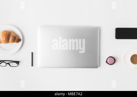 flat lay with digital devices, eyeglasses and breakfast on white tabletop Stock Photo