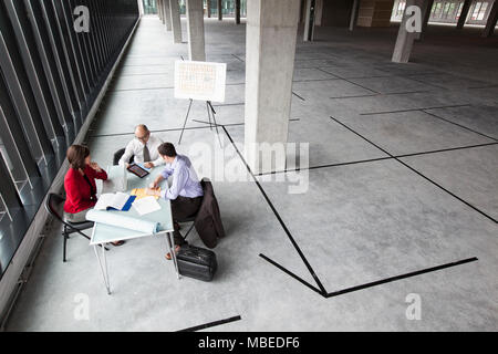 Asian architect with caucasian man and woman planning workspace in a new raw office location. Stock Photo