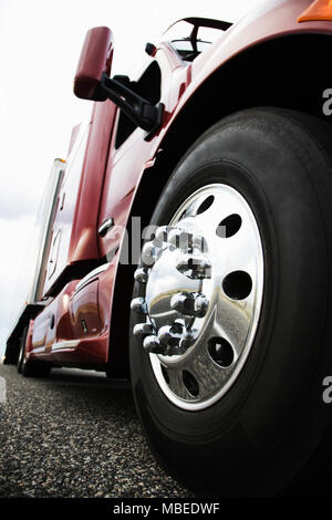 Close up 3/4 angle view of the cab and front tire on a  commercial truck on the road at sunset. Stock Photo