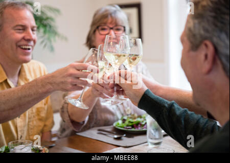 Senior couples toasting a home dinner party with glasses of white wine. Stock Photo