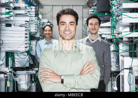 Mixed race team of technicians working on computer servers in a computer server farm. Stock Photo