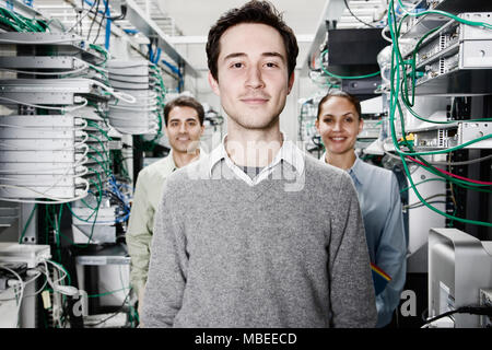 Mixed race team of technicians working on computer servers in a computer server farm. Stock Photo
